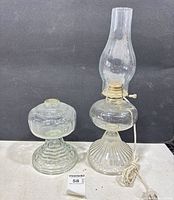 Two clear glass oil lamps side by side showing overall form