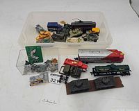 Overview of all toys laid out: locomotive, fire truck, tank models, plastic bins with vehicles and soldiers