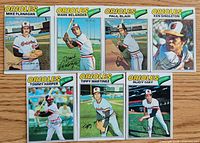 Front view of seven 1977 Topps Baltimore Orioles baseball cards arranged on wood surface