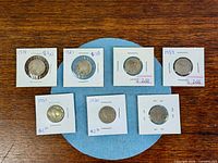 Seven of the eight Buffalo nickels in holders on table