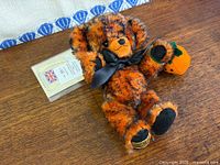 Front view of teddy bear showing overall appearance, bow, and pumpkin accessory