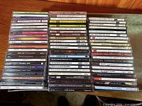 Four tall stacks of mixed rock, pop and classical CDs on wooden surface