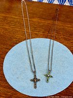 Both sterling silver cross pendants on chains displayed side by side