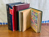 four closed albums with one green album open showing mounted US commemorative stamps