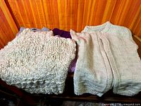 stack of four folded sweaters on wooden surface