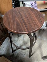 Full view of stool showcasing round wood seat and metal legs