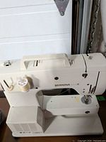 Front and top view of the Bernina Sport sewing machine with handle and cover in place