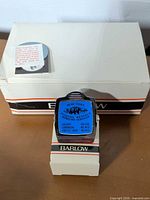 Closed white Barlow box with one magnetic clip displayed on smaller stand