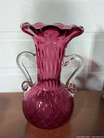 Front view showing cranberry glass vase, clear applied handles, diamond quilt pattern