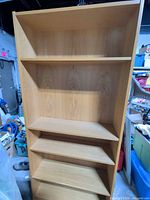 Front view showing entire tall wood bookcase with five shelves