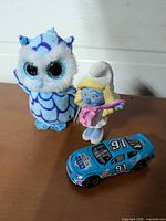 Group shot of Ty owl plush clip, Smurfette figure, blue #91 toy car