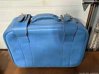 Front view of blue suitcase showing buckle straps and handle