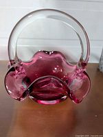 Front view of cranberry glass basket showing clear applied handle and ruffled rim