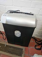 Front view showing black bin, silver top, viewing window and power cord