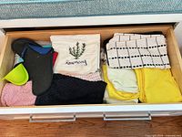 Drawer view showing mixed towels, embroidered napkin, oven mitt, silicone mitt, yellow towels