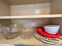 Shelf view showing all bowls, red silicone plate and patterned plates