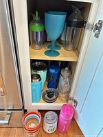 Cabinet showing majority of drinkware pieces on two shelves and three items on floor