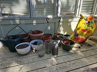 Full lot on deck showing planters, watering can, hanging frames, potting mix bag