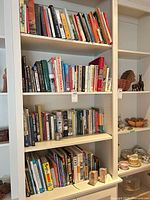 Full view of four shelves containing assorted books and stone bookends