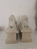 Front view of both resin lion bookends on plinths