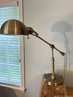 Full view of brass adjustable desk lamp on table