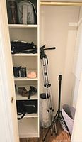 Closet shelves showing lenses, instant camera, camera bags, tripod, light stand, paper roll