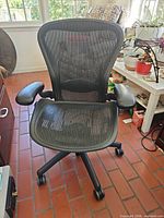 Front view of Herman Miller Mirra chair showing mesh seat/back, armrests and caster base