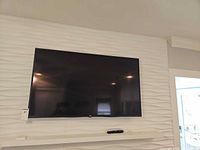 Front view of LG TV wall-mounted above shelf