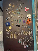overview of entire lot of assorted earrings on table