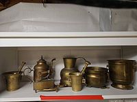 Shelf view of all six brass pieces side by side