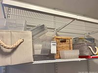 Shelf with beige fabric bin, stacked clear plastic trays, wicker basket, gray fabric bin, Space Bag box