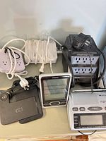 Group view showing surge tower, power strips, wireless charger, weather station display, weather radio and adapter