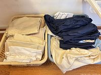 Two laundry baskets containing beige, white and navy bedding pieces