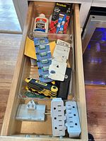 Open drawer showing glue bottles, battery packs, Husky tool, adapters