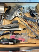 Drawer containing assorted stainless and plastic utensils plus syringe and thermometer
