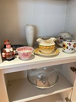 Shelf view showing multiple porcelain items and glass dome