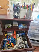 desk hutch with open drawer showing pens, pencils, scissors, calculator, staples, tape and other accessories