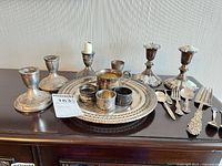 Group shot of all candlesticks, tray, cups and flatware on sideboard