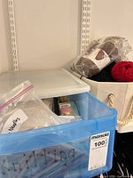 Blue plastic bin labeled knitting next to white basket with red and brown/tan Lion Brand yarn skeins