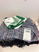 Stack showing white-green silk-like scarf on multicolor knit scarf