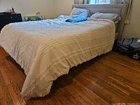 Bed fully assembled with bedding, shows overall size and upholstery color