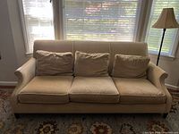 Front view of beige three-seat sofa with cushions
