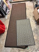 Brown natural fiber runner and grey/cream Safavieh rug on concrete floor