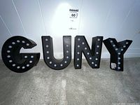 Front view showing letters G U N Y with light bulb sockets