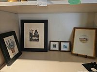 Shelf view of all five framed prints and display easel