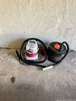 Both vacuums side by side with hose and wand on floor