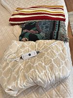 Beige Sunbeam electric throw with controller, crocheted striped throw, tapestry throw folded on top