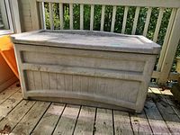 Front view of Suncast gray resin deck box on deck floor
