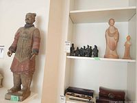 Full view of large terracotta warrior, pottery monks and miniature figures on shelving