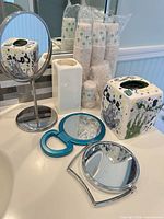 All items grouped on bathroom counter showing vanity mirror, handheld mirror, compact mirror, ceramic pieces and sealed cups
